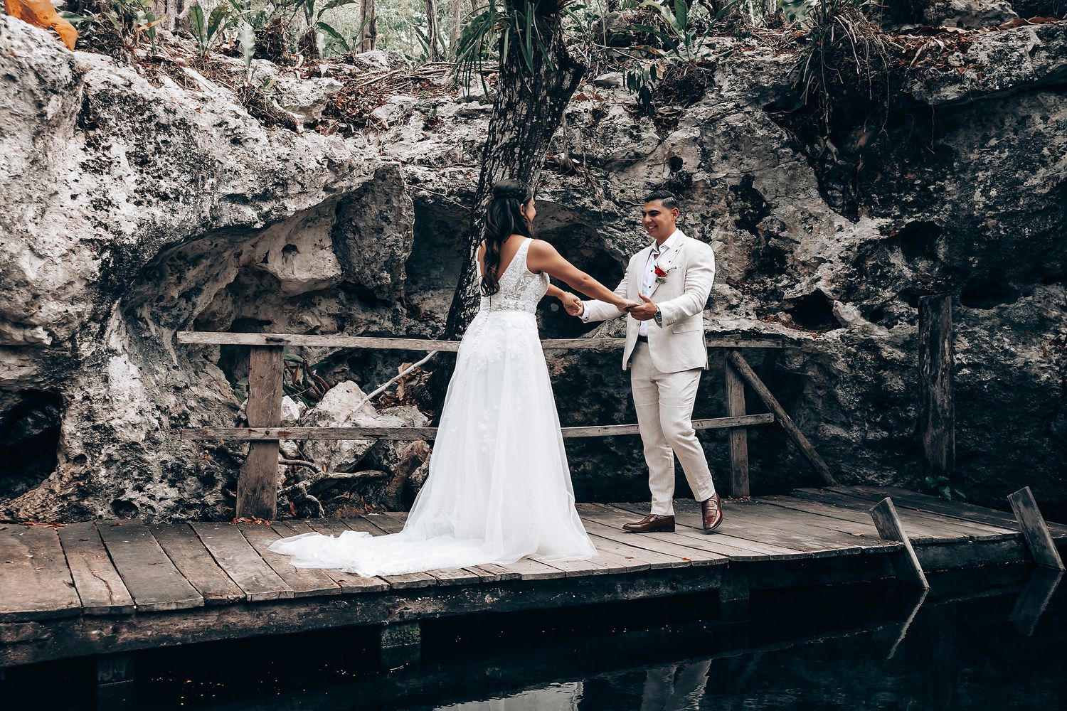 Elegant wedding ceremony taking place in a natural limestone cave with water features.