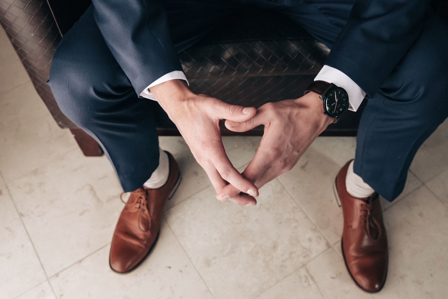 Overhead view of groom in navy suit with brown leather dress shoes and watch.