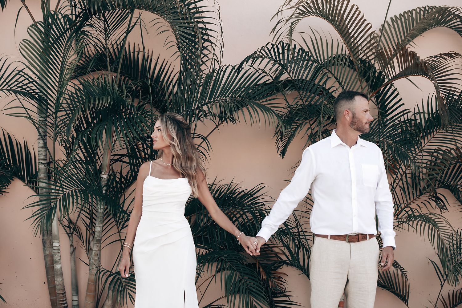 A couple in wedding attire standing together in a lush, misty outdoor setting.