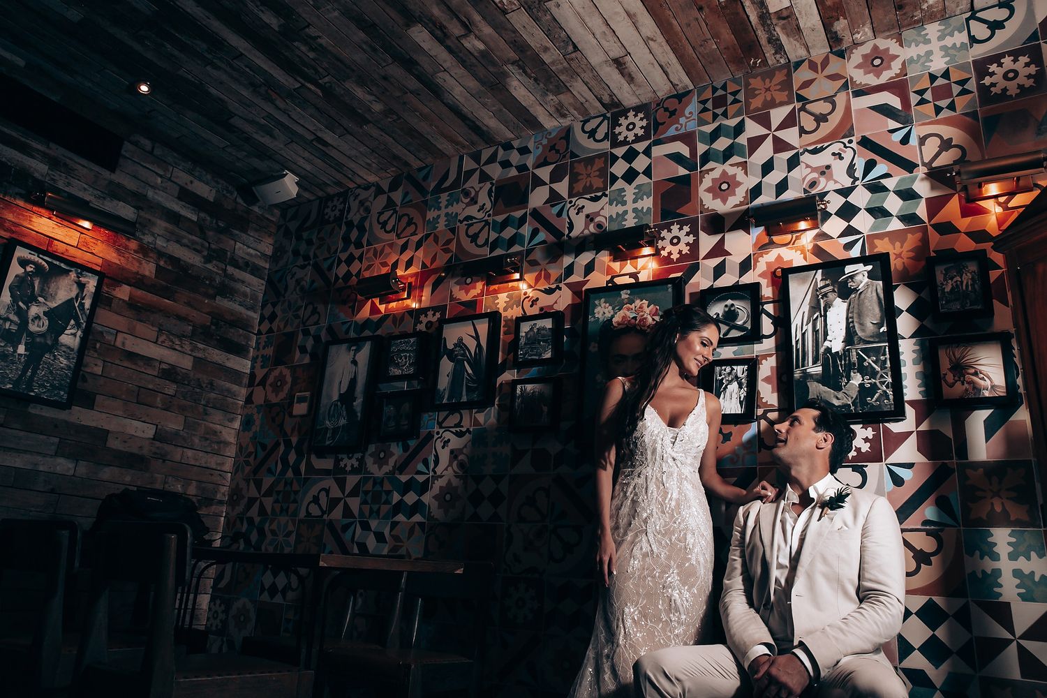Artistic wedding photo in moody industrial venue with decorative lighting and wooden details.