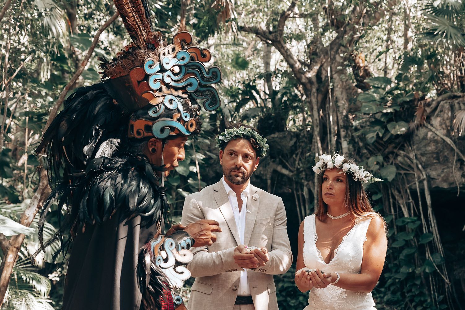 Couple participates in traditional Mayan blessing ceremony surrounded by tropical foliage.