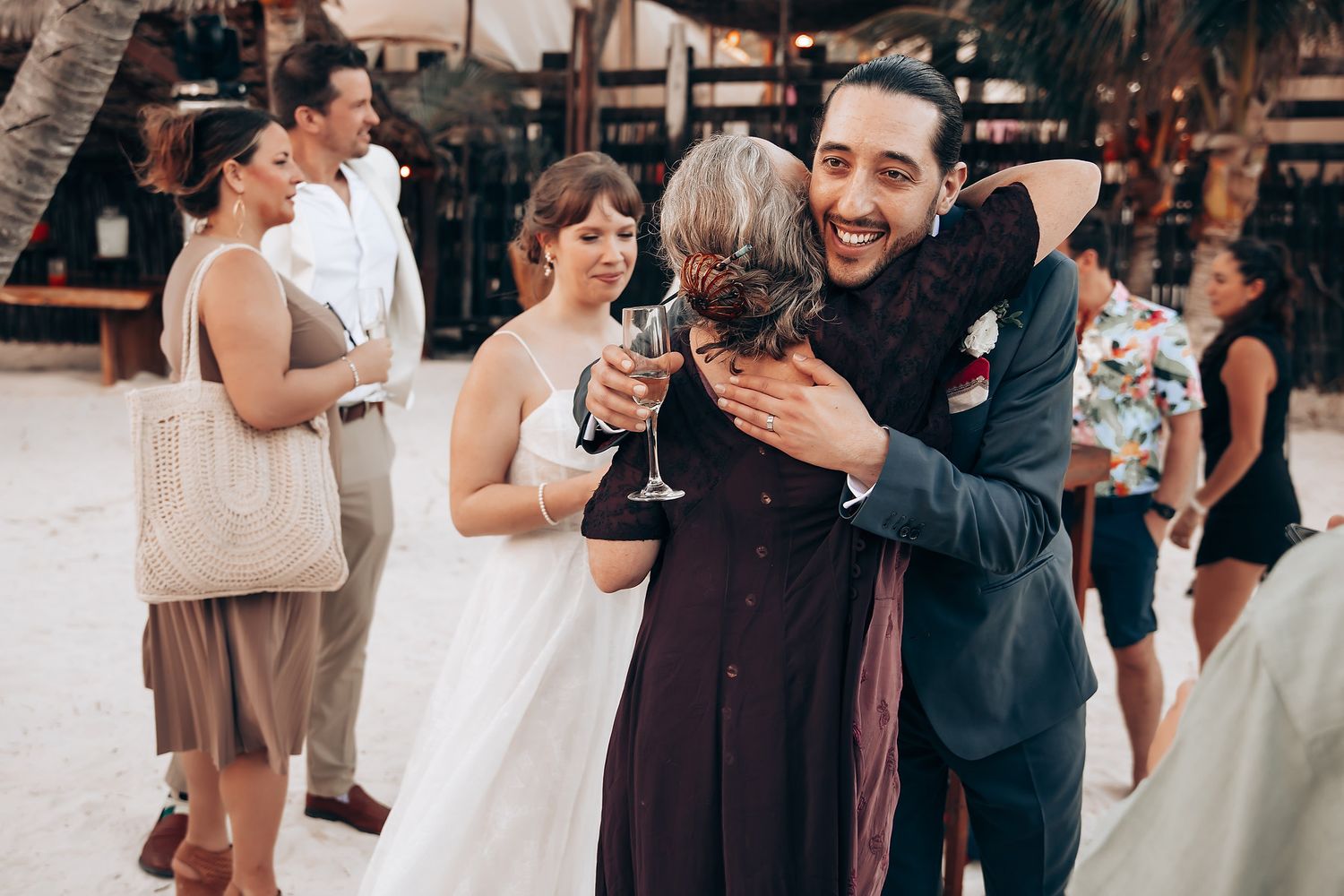 Wedding guests mingle and celebrate during an outdoor reception with string lights overhead.