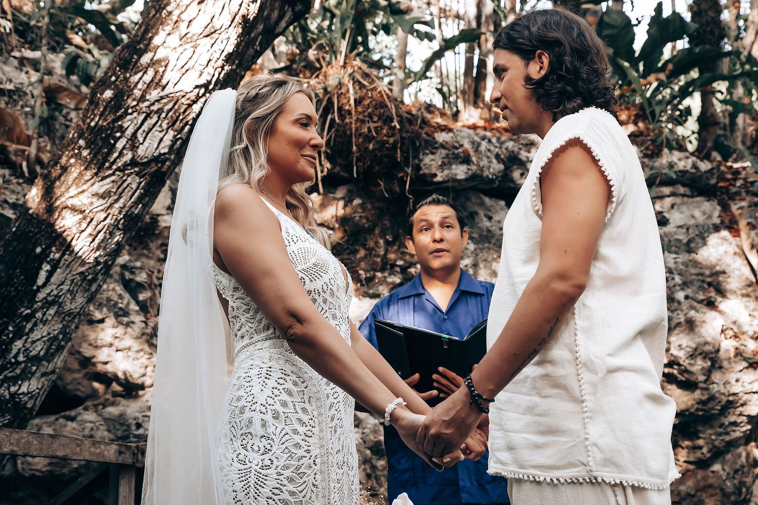 A wedding couple shares an intimate moment together outdoors while guests look on during their celebration.