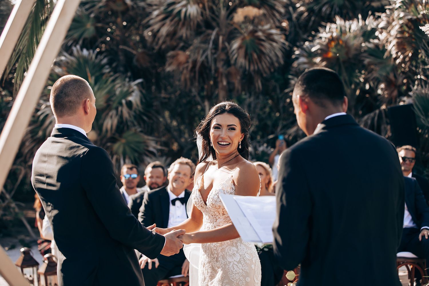 Wedding guests celebrating during an outdoor reception with natural lighting.