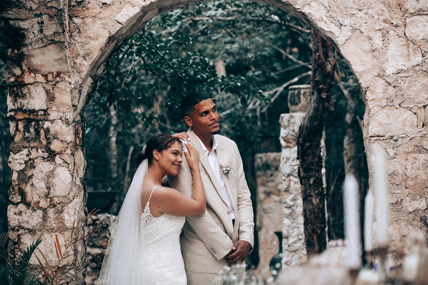Wedding couple sharing intimate moments against stone archway backdrop.
