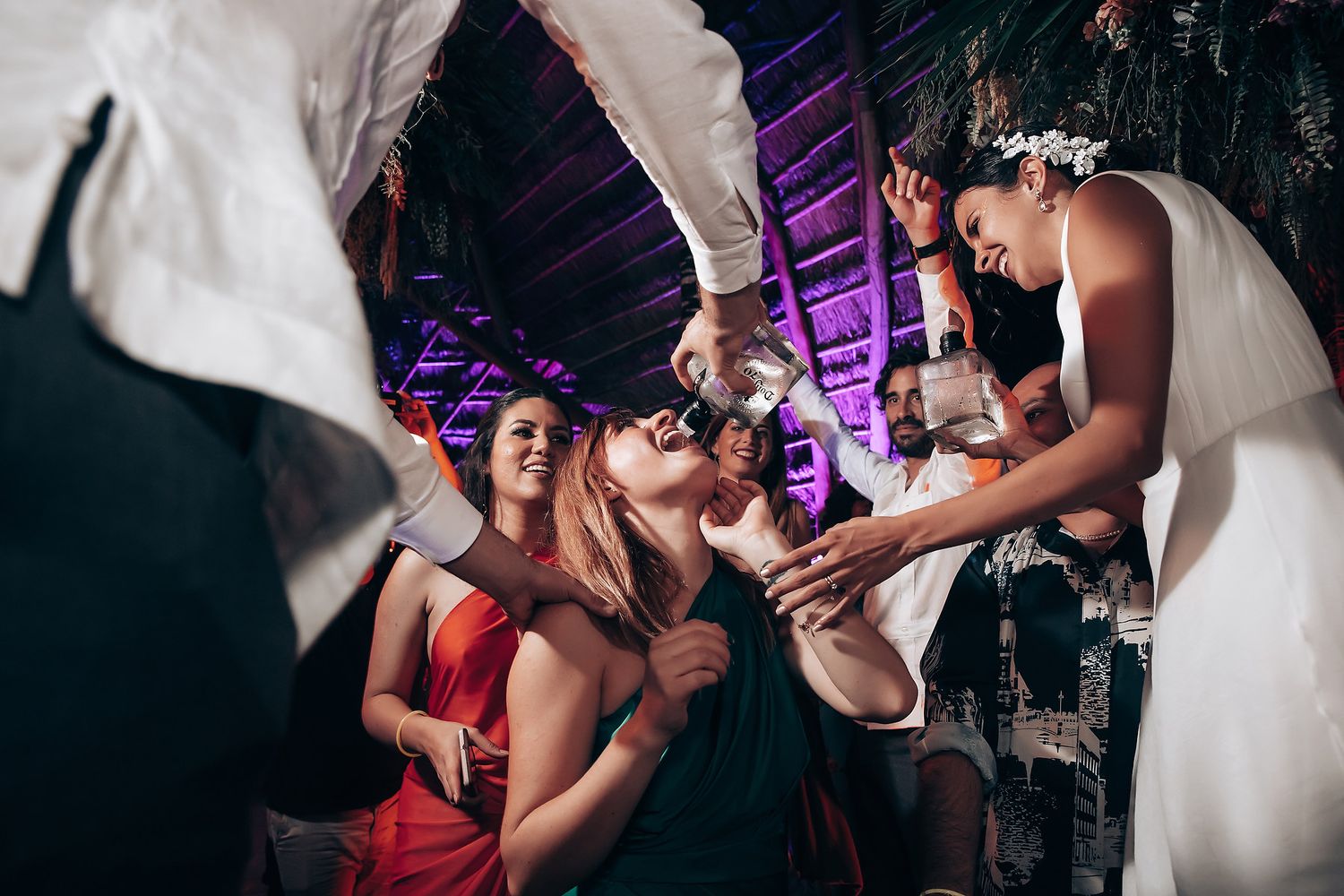 Wedding guests gather together for drinks and celebration during an energetic reception party.