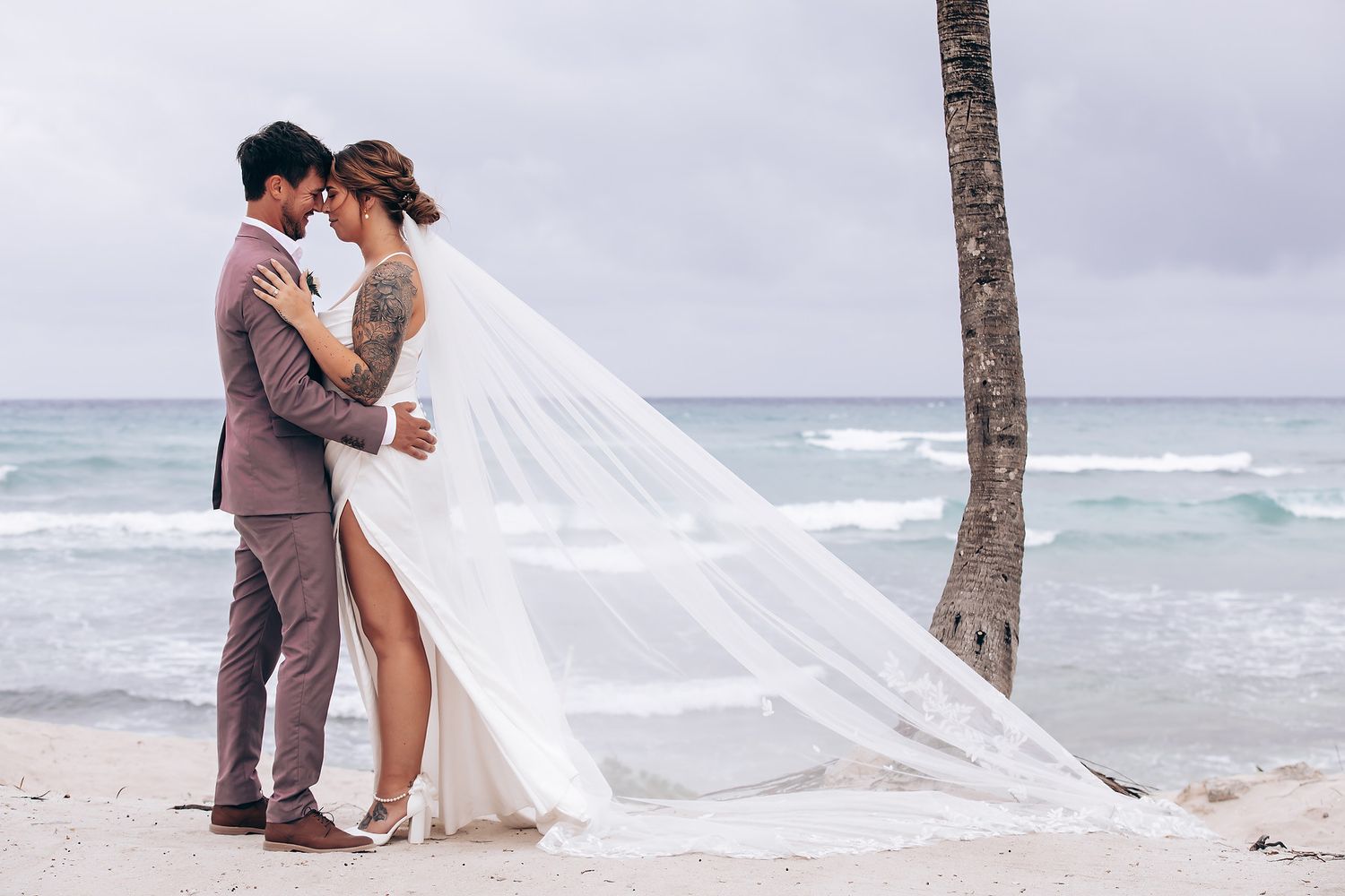 A romantic beach wedding scene with a flowing white dress and gentle waves along a palm-lined tropical shore.