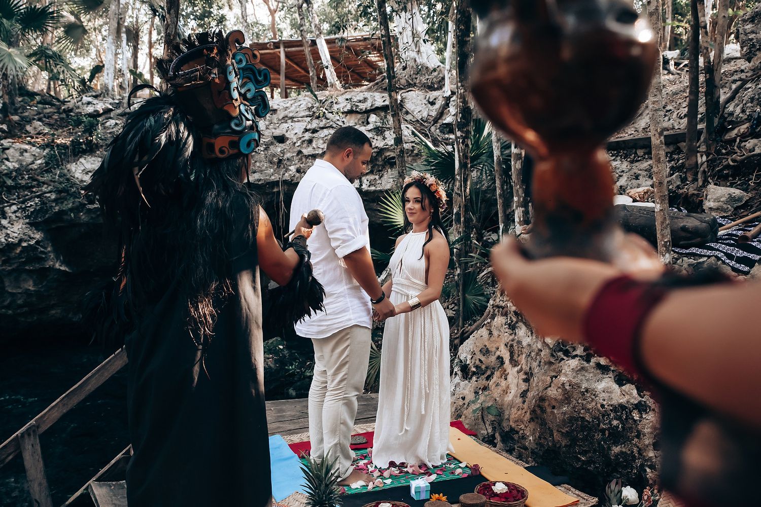 A spiritual ceremony takes place in a wooded outdoor setting with traditional decorations and rituals.