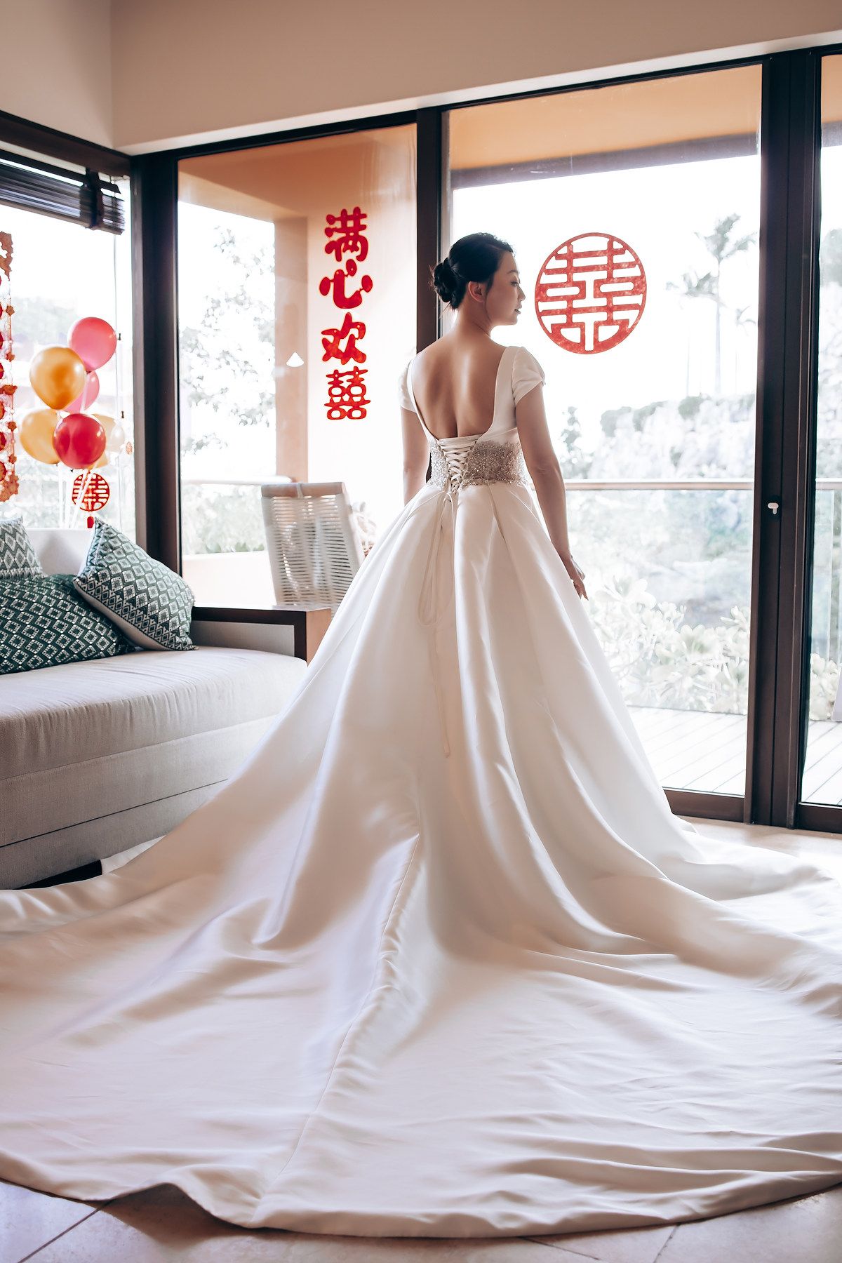 Stunning white wedding gown with cathedral train against Chinese wedding decorations.