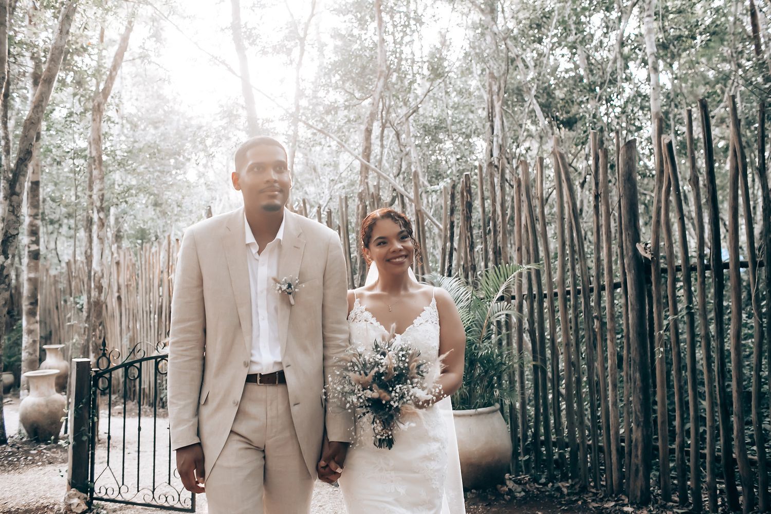 Intimate forest wedding ceremony with guests gathered under trees and floral decorations.