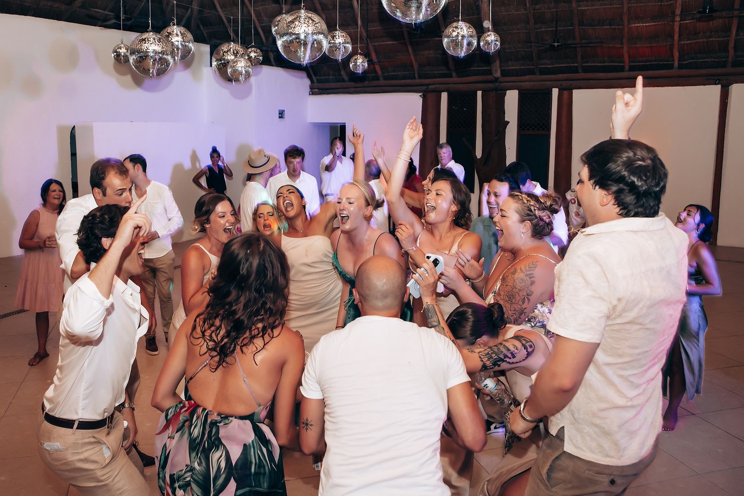 Lively wedding celebration with guests dancing and cheering on the dance floor.