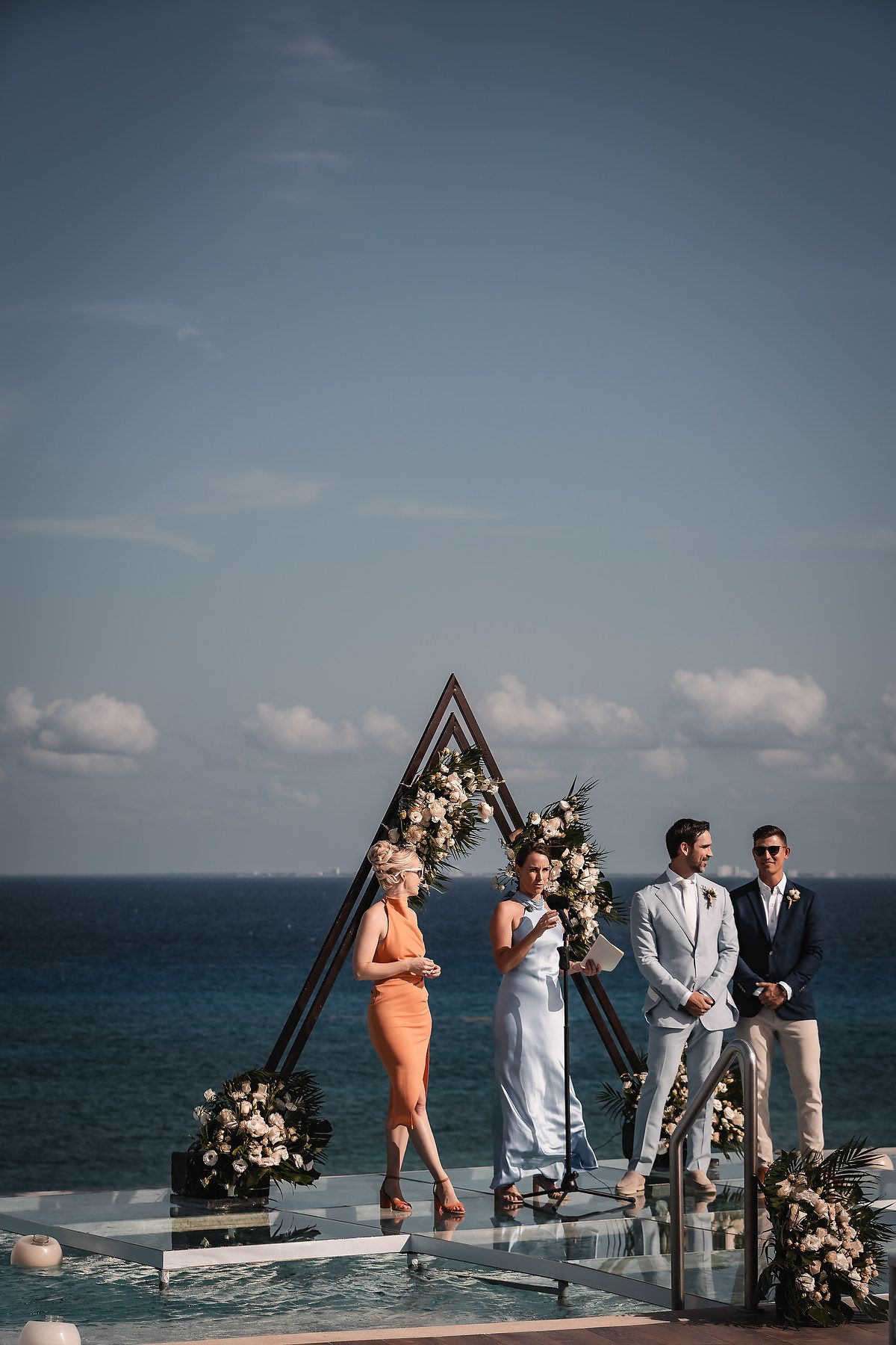 Wedding ceremony in progress on wooden deck overlooking dramatic ocean views.