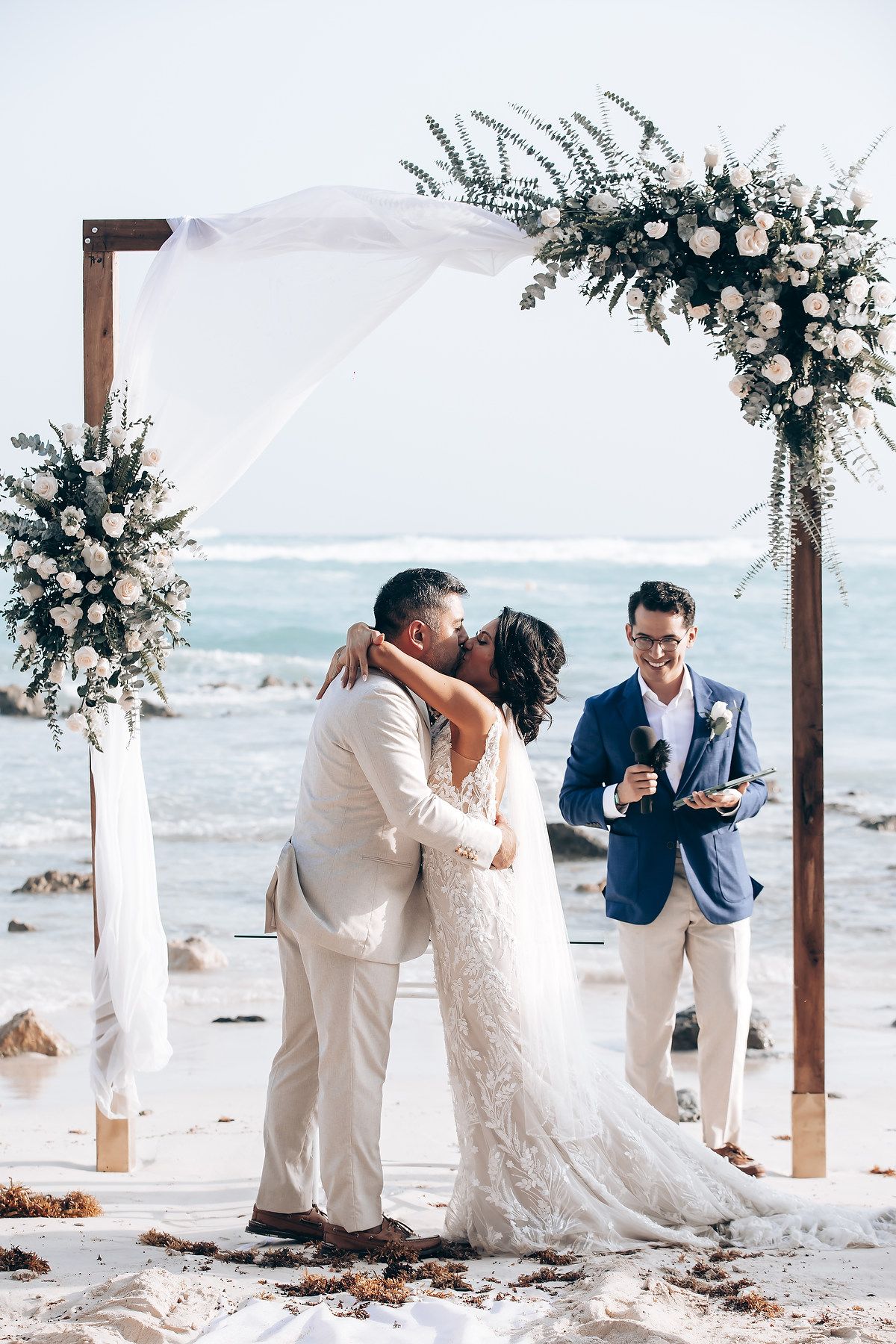 Wedding ceremony moments captured in sequence showing a couple exchanging vows under a floral arch by the beach.