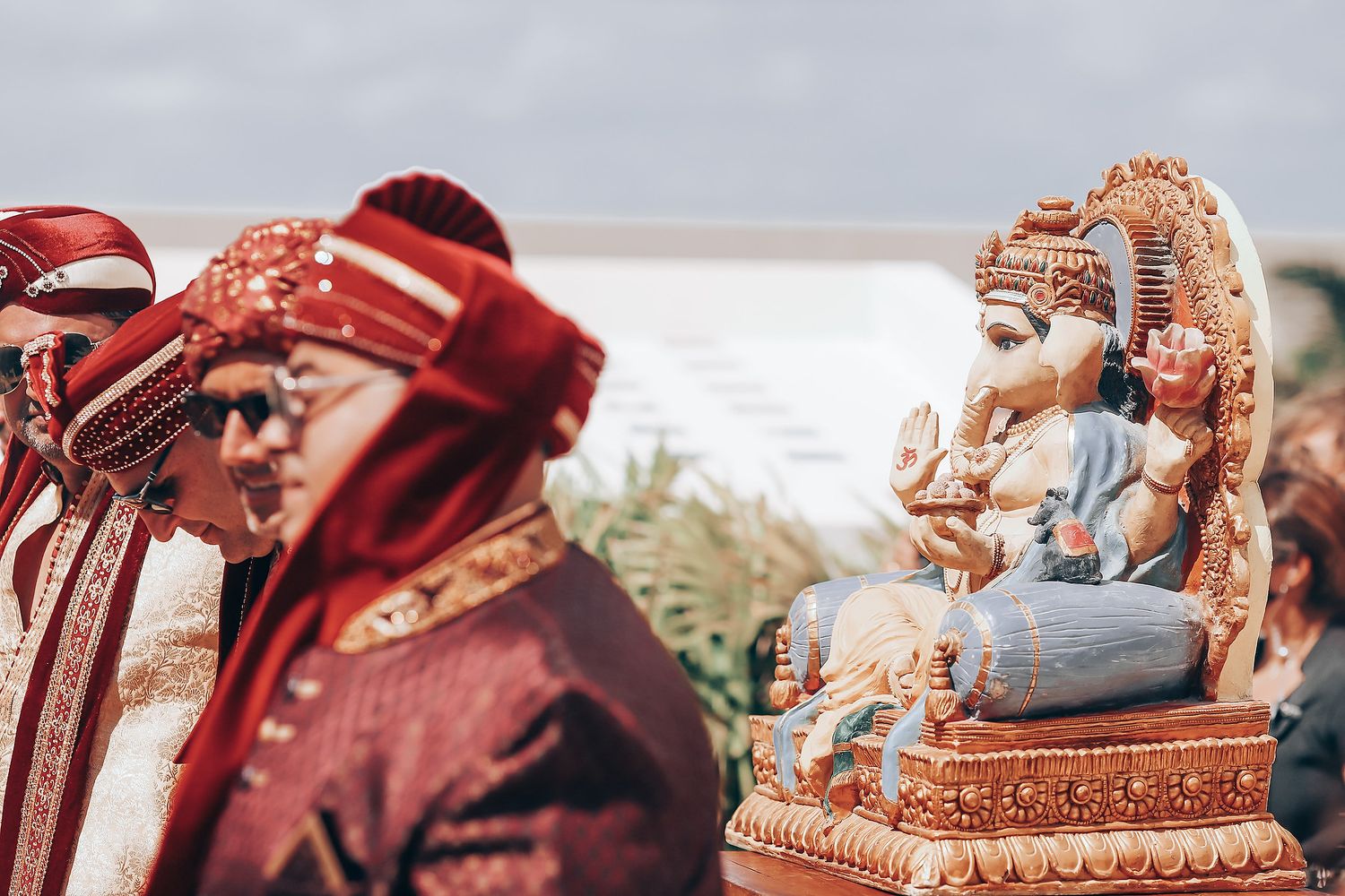 A traditional Indian wedding ceremony with the couple seated on ornate red and gold decorated chairs during rituals.