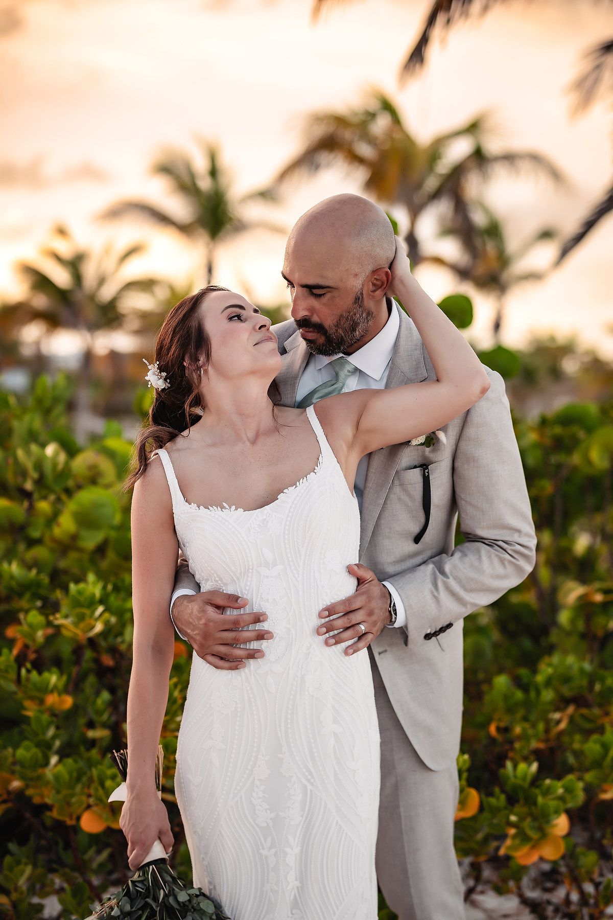 A romantic sunset beach wedding portrait among tropical palm trees.