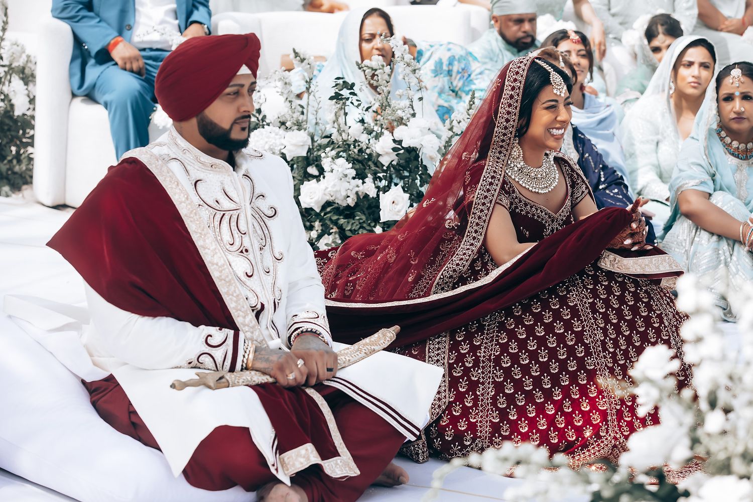 Elegant beachside wedding ceremony with burgundy and white traditional attire.