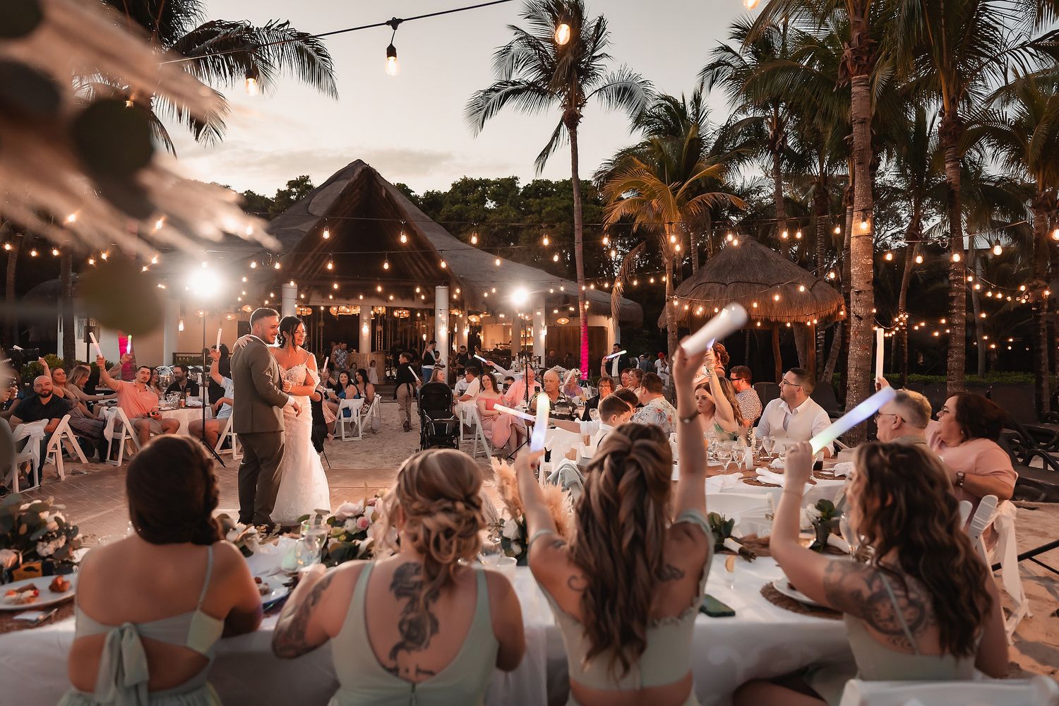Evening beach wedding reception with string lights creating a romantic atmosphere.