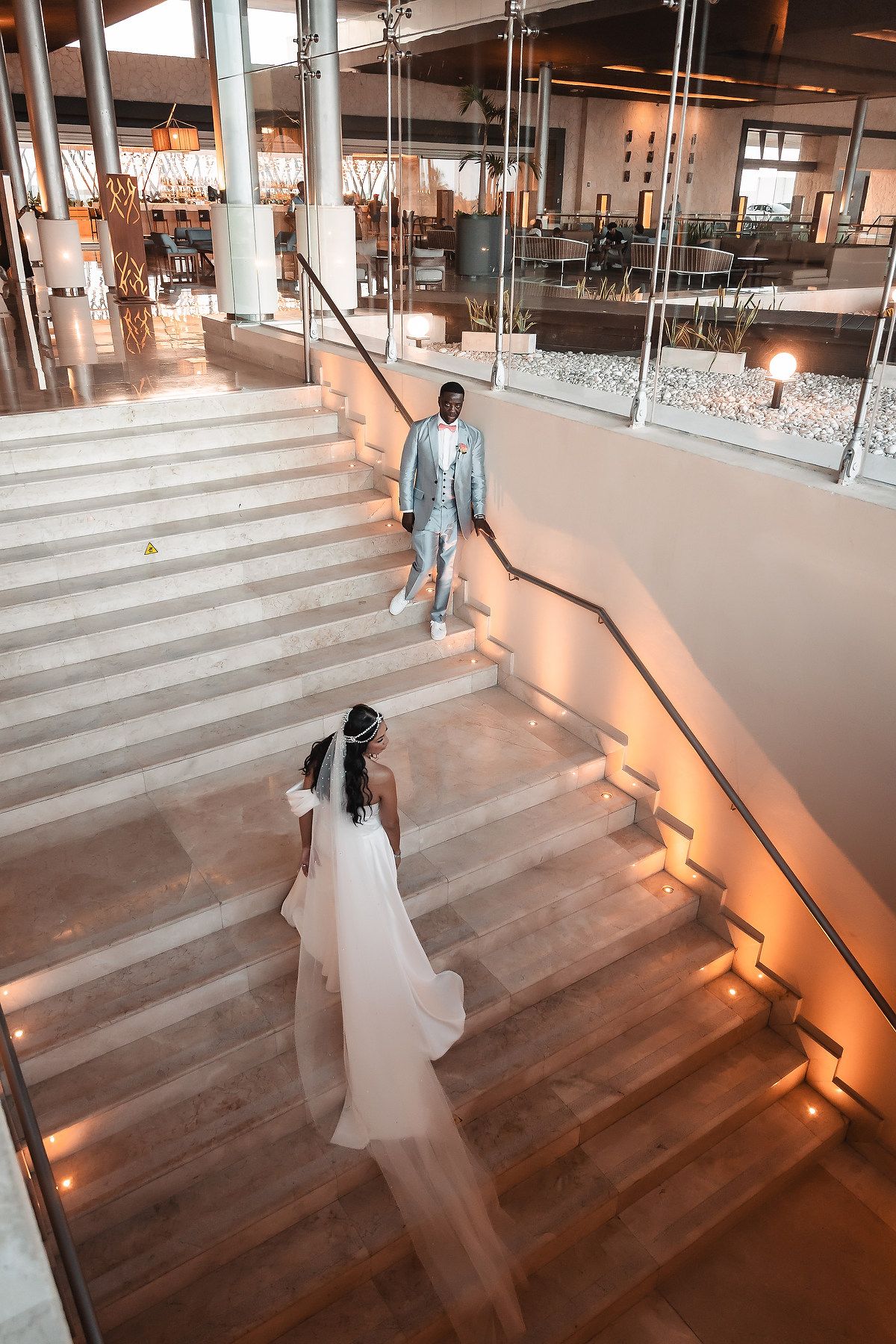 Wedding couple on illuminated wooden staircase in an industrial-style venue.
