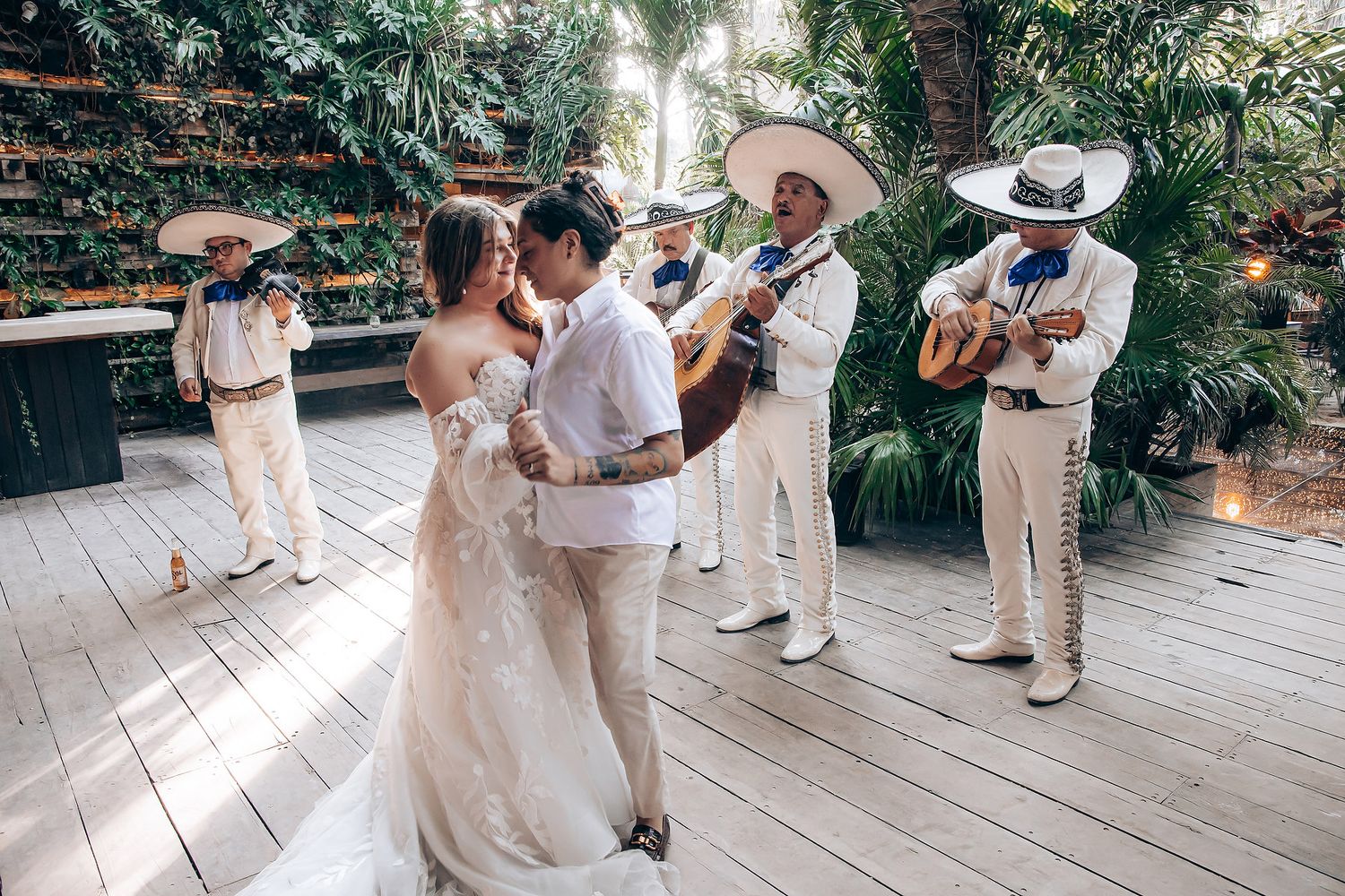 Wedding party members dance and celebrate on an outdoor wooden deck.