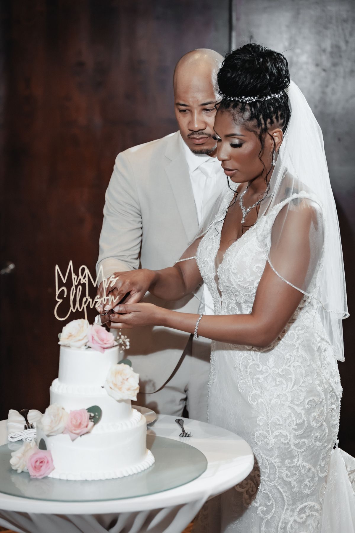 Bride and groom cutting their white three-tier wedding cake together at their elegant reception ceremony.