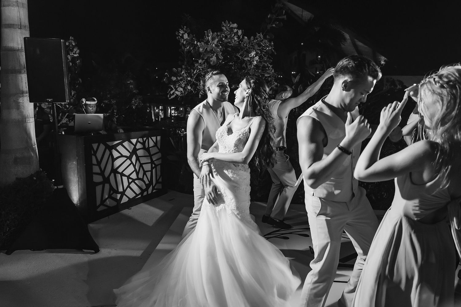 Black and white photo of a bride and groom sharing their first dance surrounded by guests at an elegant evening wedding.