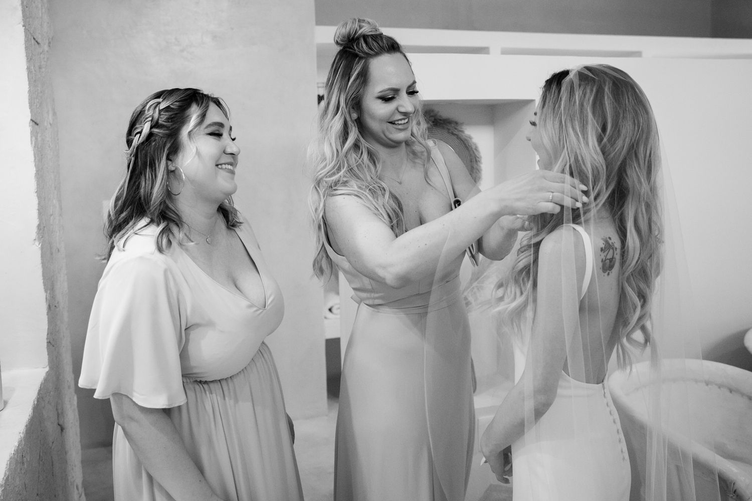 Bridesmaids helping bride get ready in black and white wedding preparation photo.