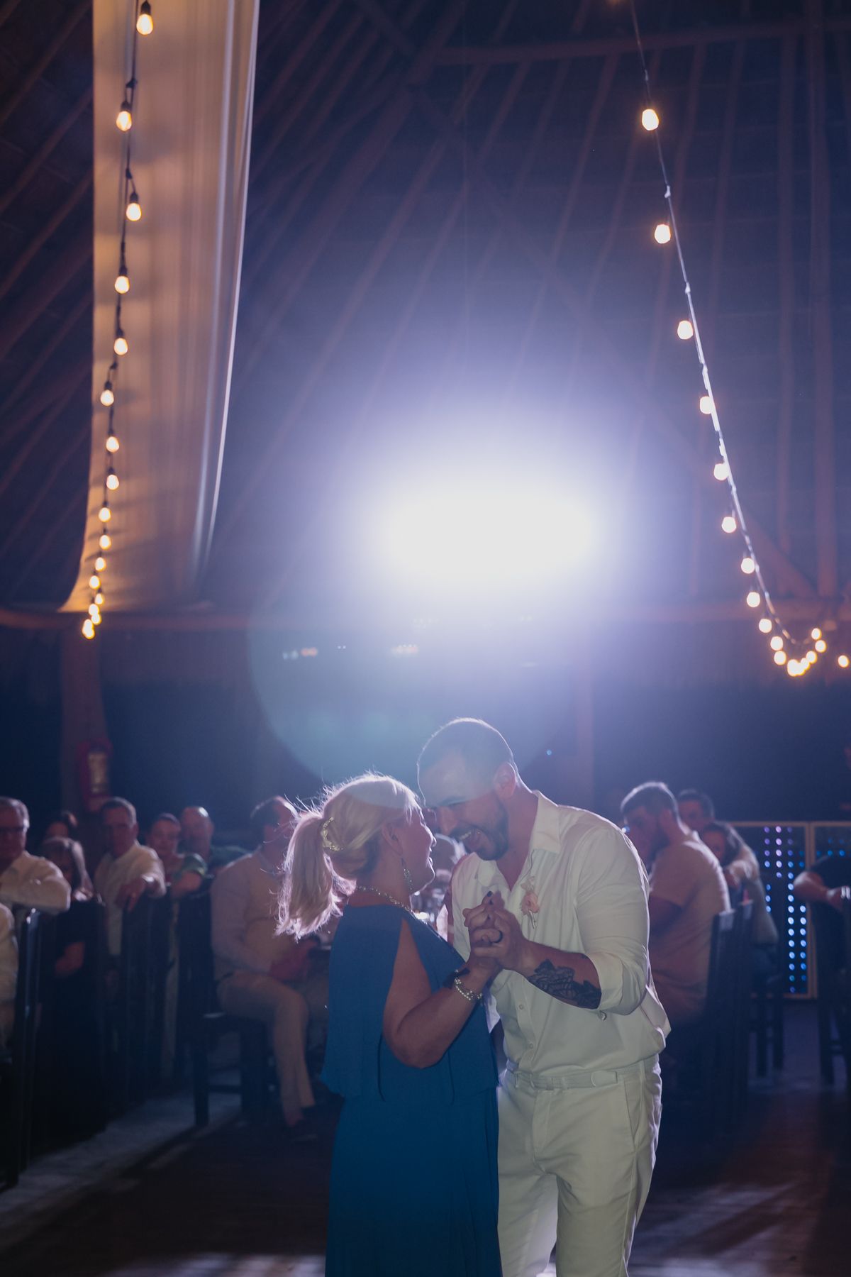 Couple sharing a romantic first dance under string lights at an elegant wedding reception venue.