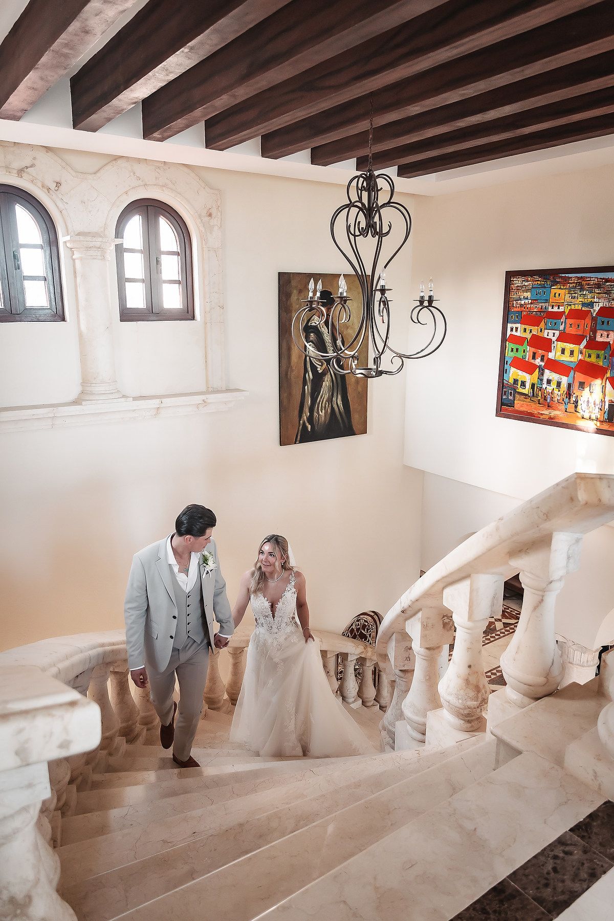 Wedding couple photographed in a rustic hallway with wooden beams and vibrant wall art.