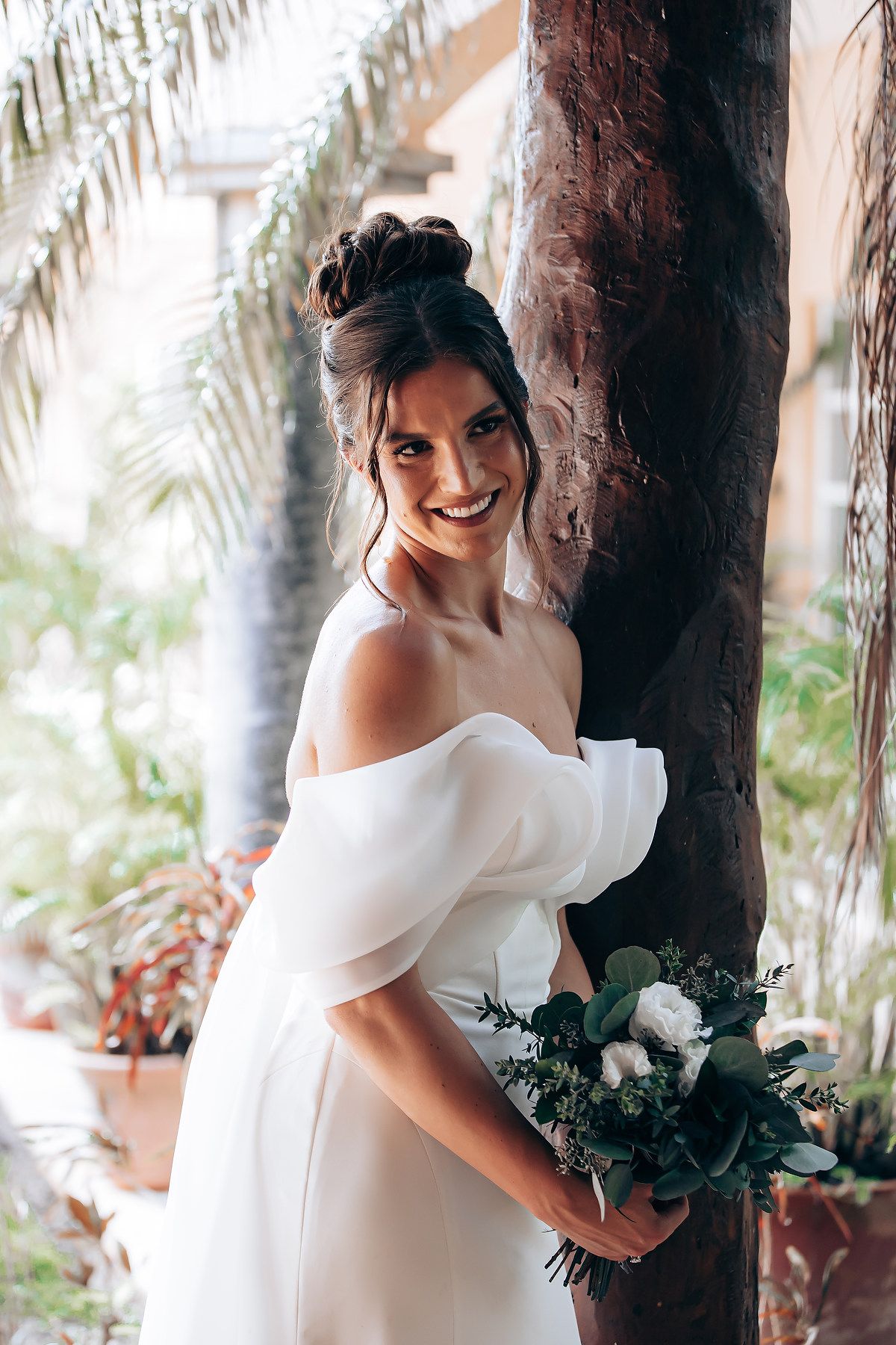 Bridal portrait session among palm trees with white dress and floral bouquet.