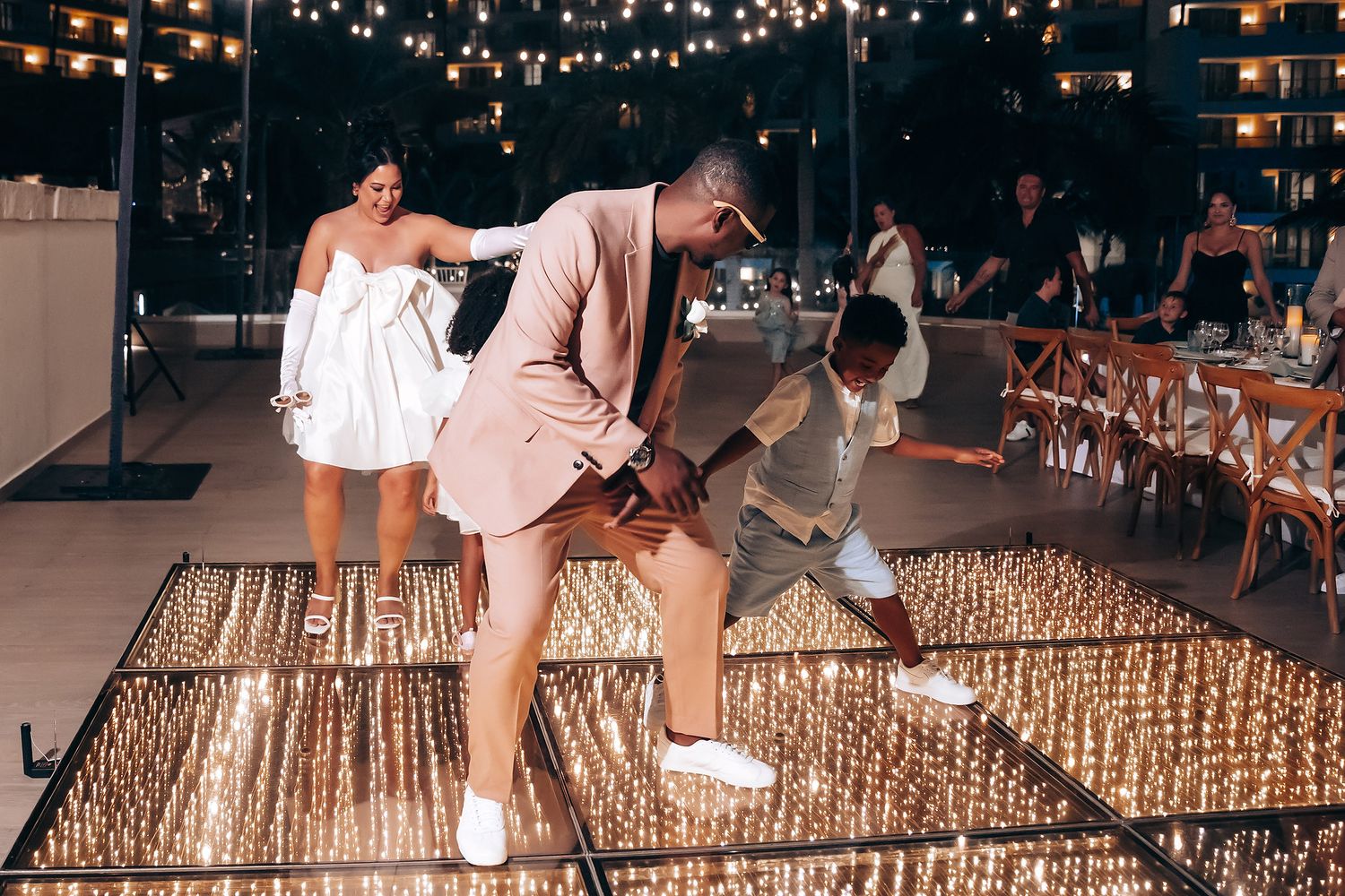 Guests enjoying an outdoor evening celebration under string lights.