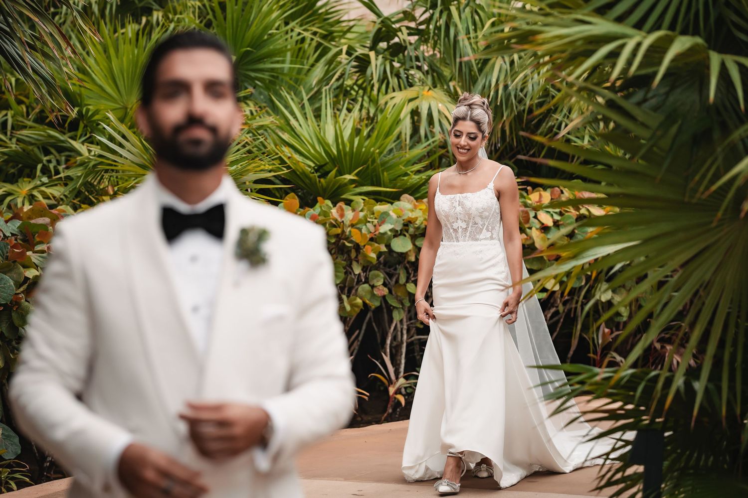 Newlyweds share intimate moments surrounded by lush tropical palm gardens.