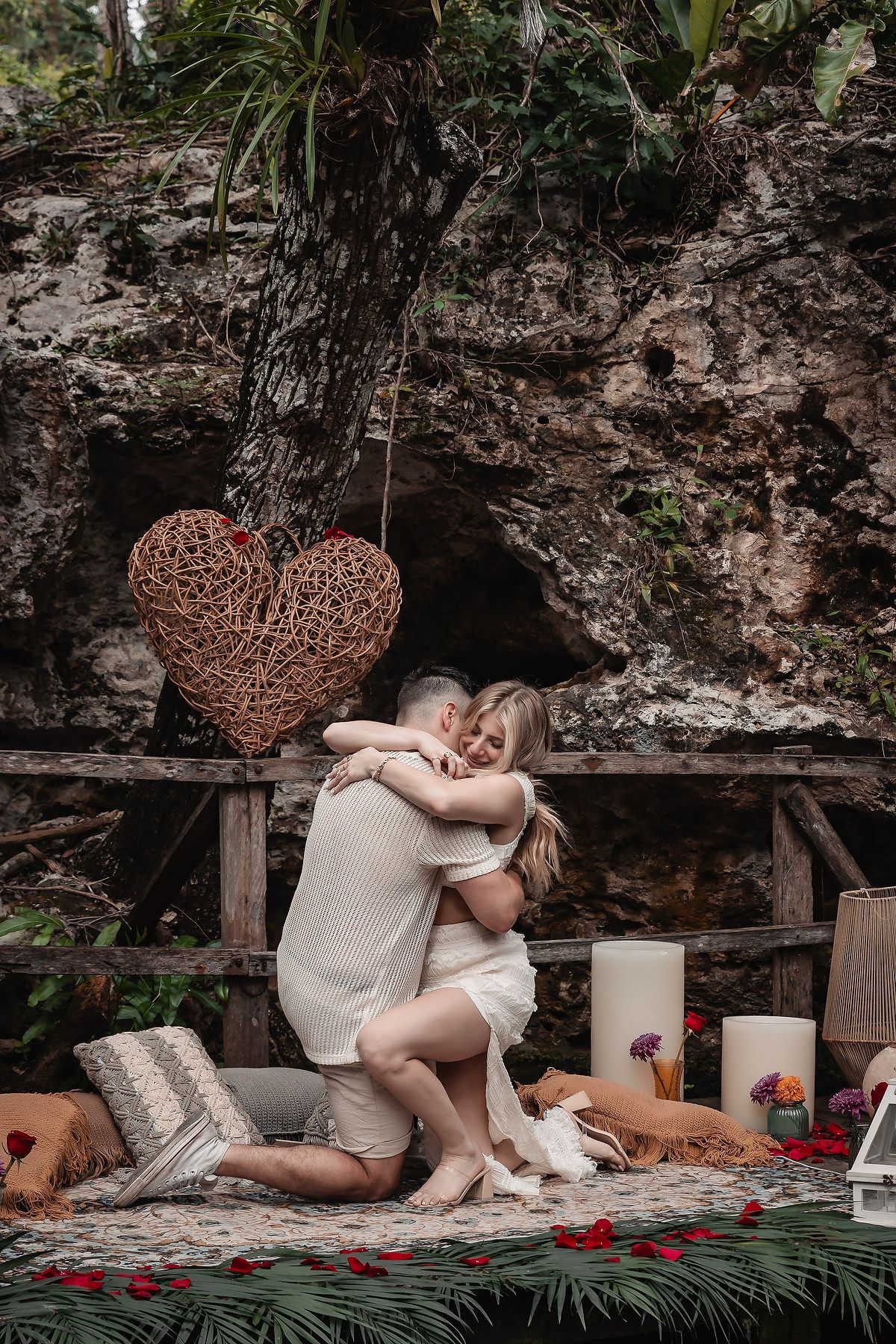 Garden setting with woven heart decor, white candles and romantic elements on stone patio.