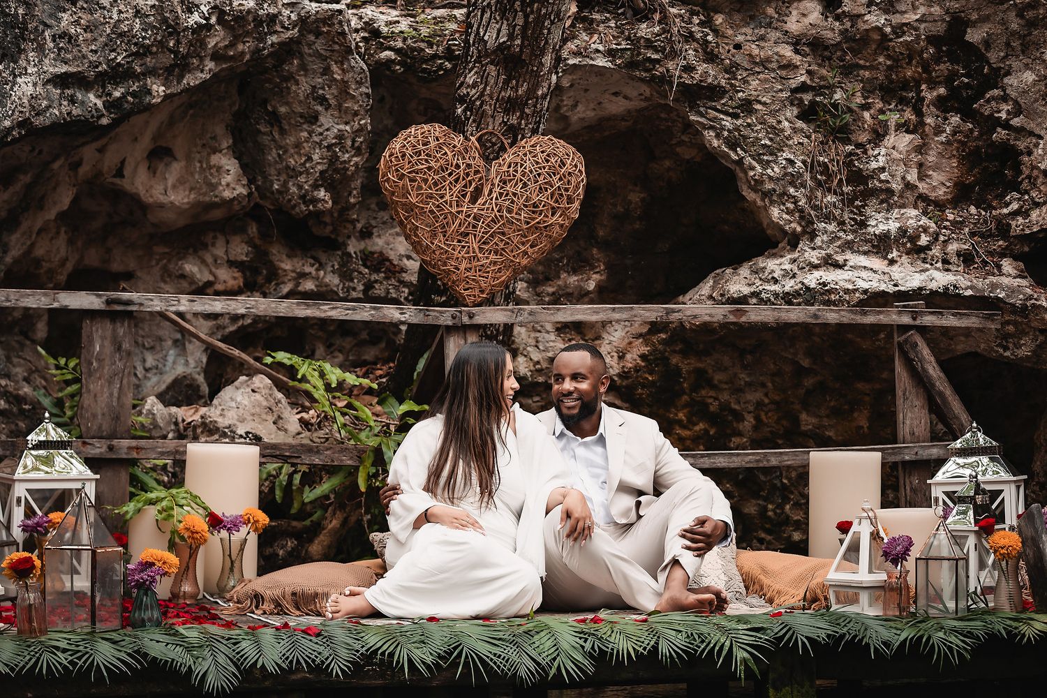 Rustic outdoor celebration decor with hanging lights and decorative elements against a rocky cave wall.