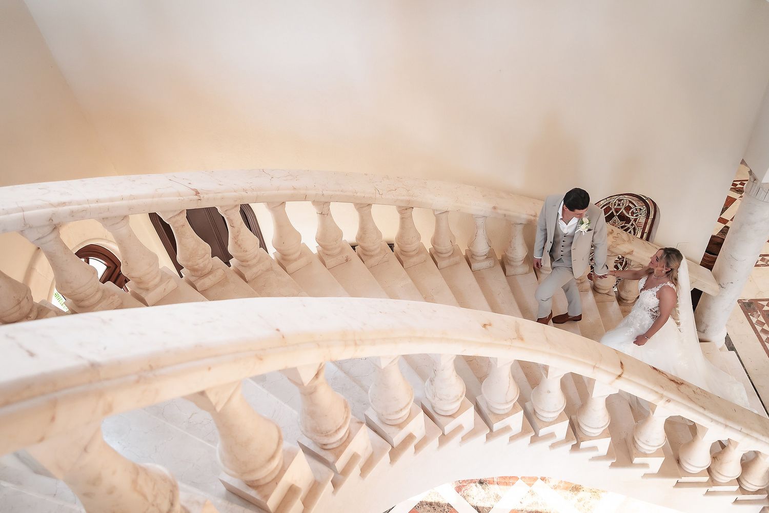 Ornate white balustrade details line a curved staircase in an elegant venue.