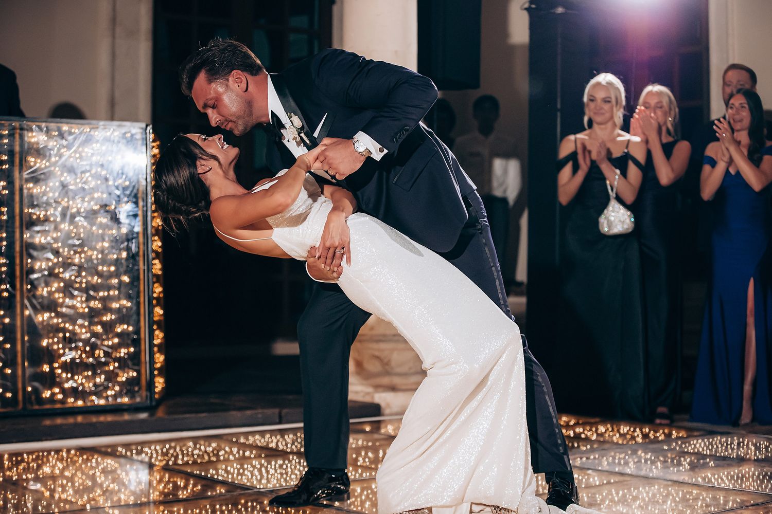 Romantic first dance moment captured under sparkling lights at an indoor wedding reception.