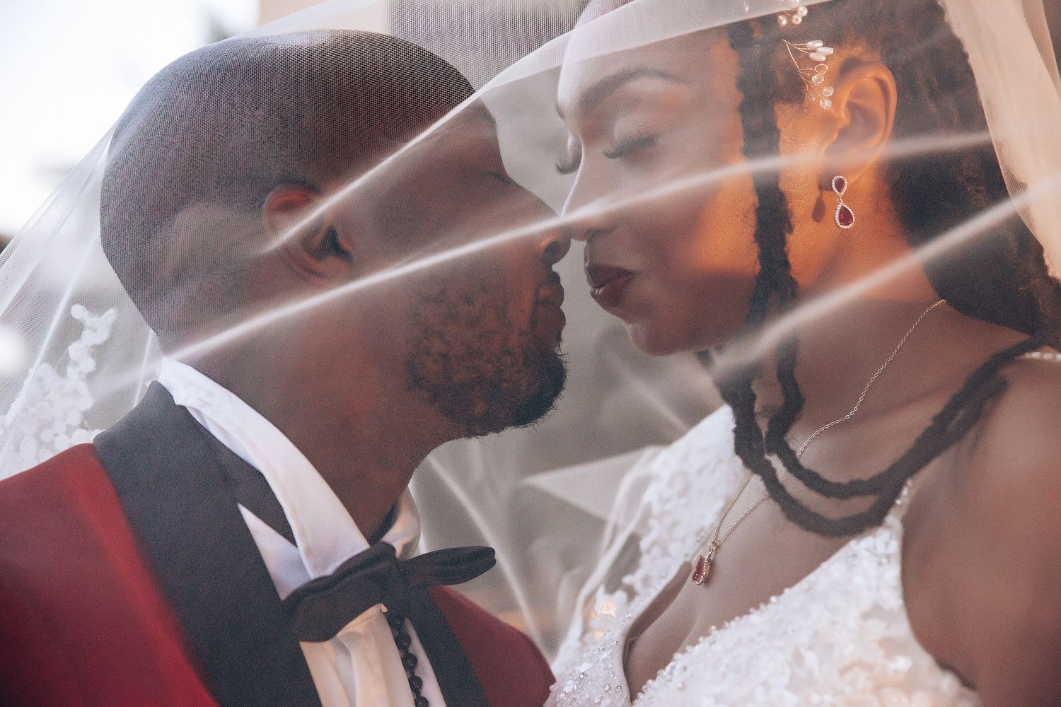 An intimate wedding moment captured through a delicate veil at an outdoor celebration.