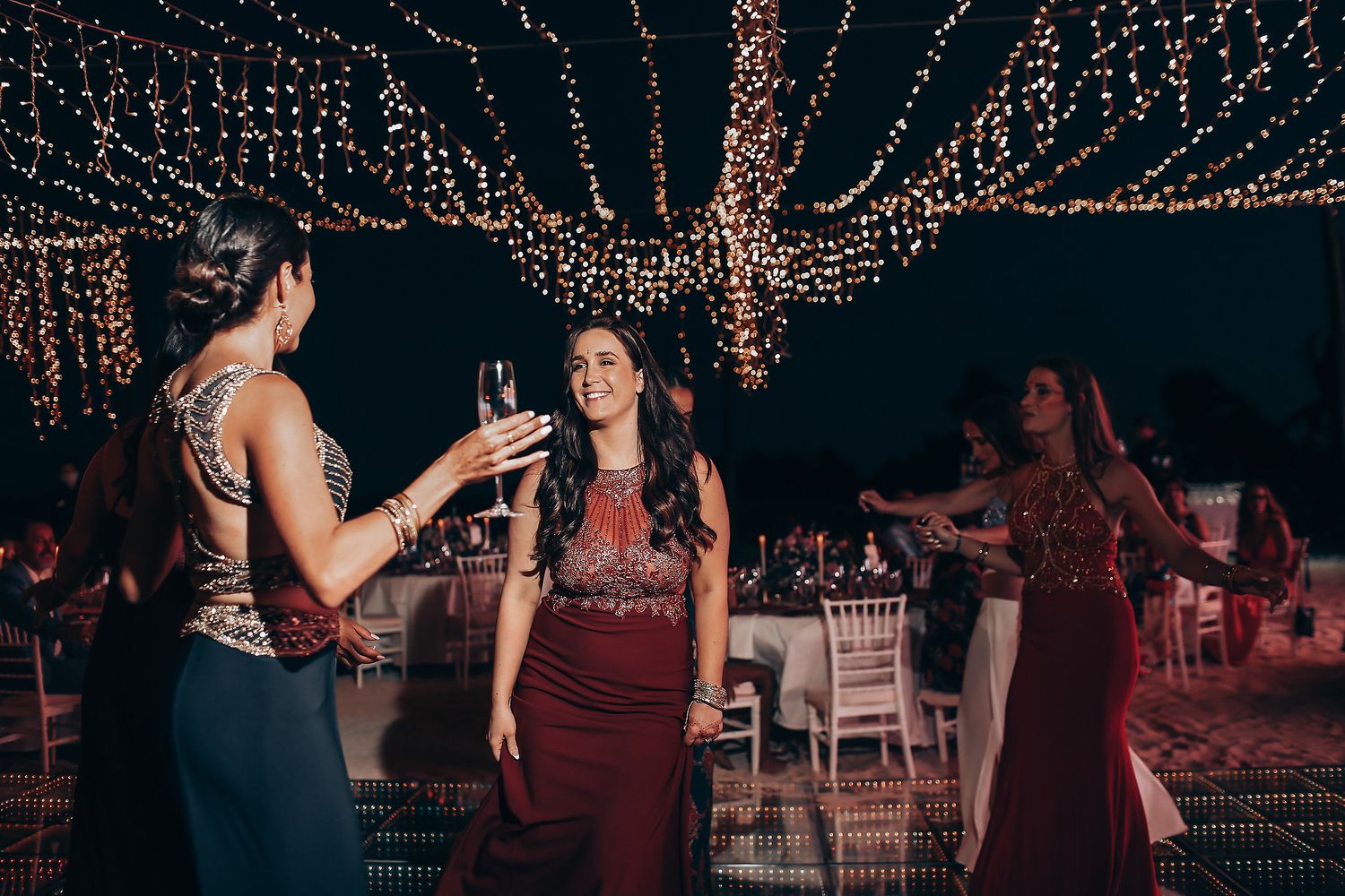 A group dances and celebrates at a wedding reception under twinkling string lights.