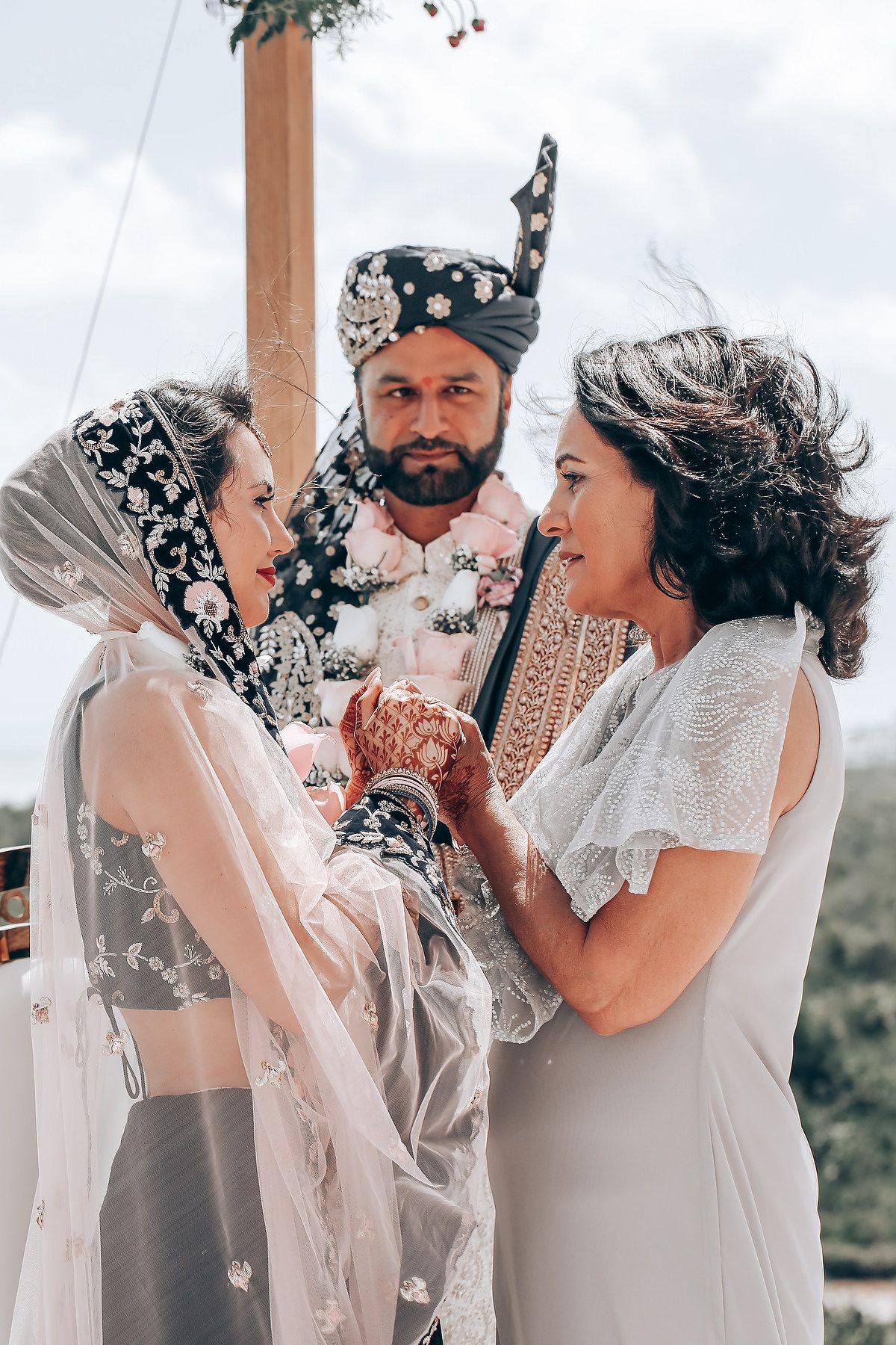 Intimate wedding portraits showing tender moments between couples in white attire against a cloudy backdrop.