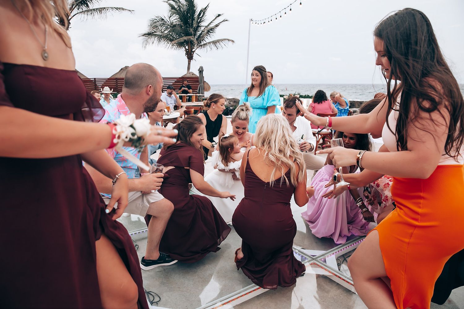 Wedding celebration with guests dancing poolside at a tropical evening reception.