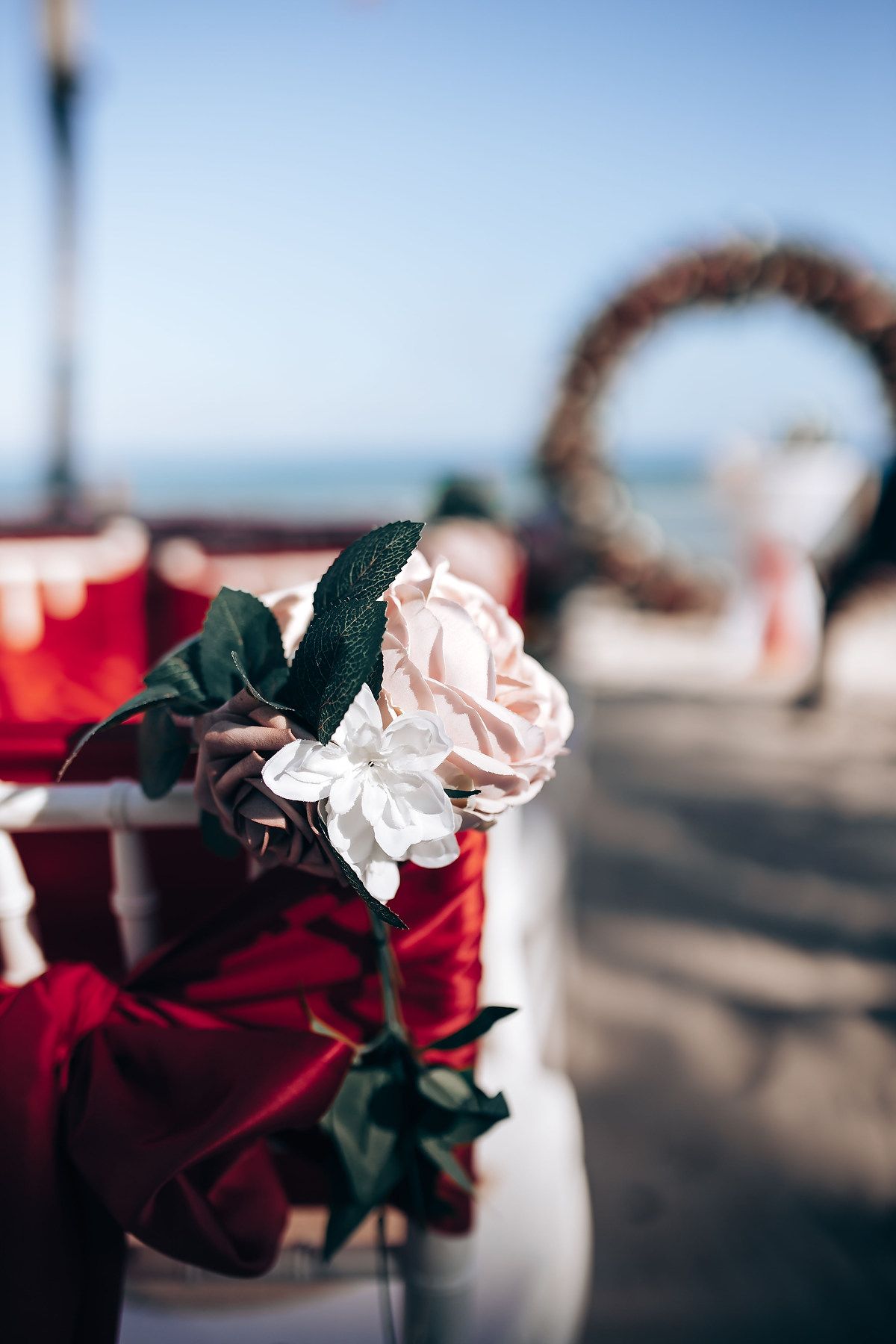 Close-up of red and white roses used as wedding decorations with blurred beach background.