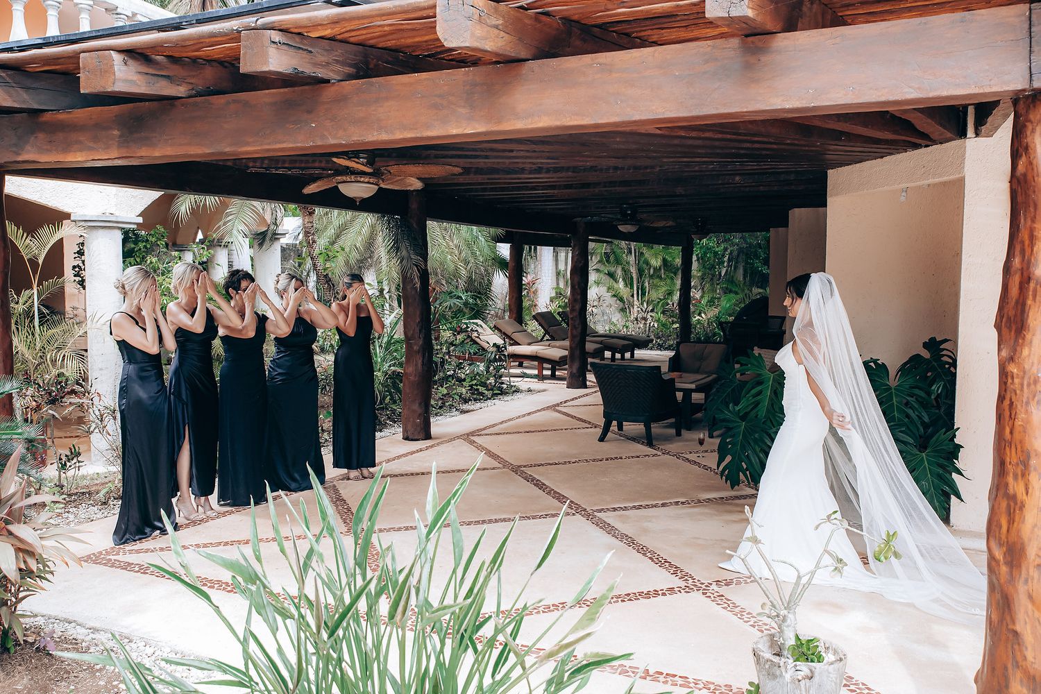 Outdoor wedding venue with wooden beams and tropical landscaping under a covered patio area.