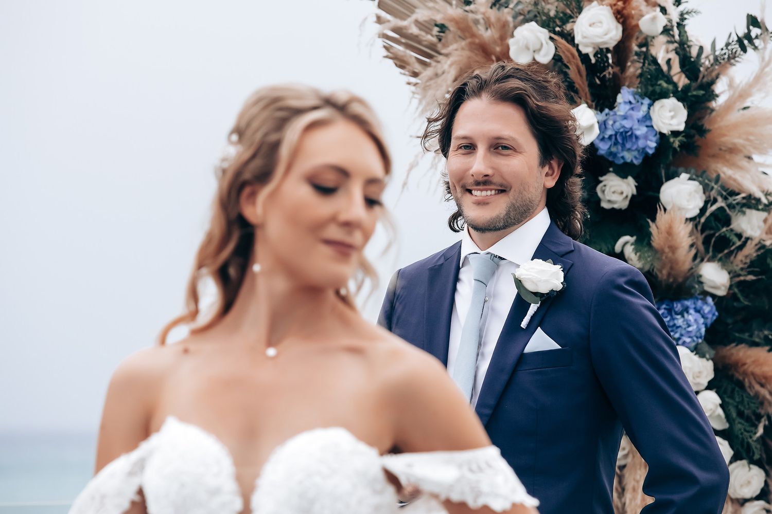 Elegant beach wedding ceremony with blue and white floral arrangements.