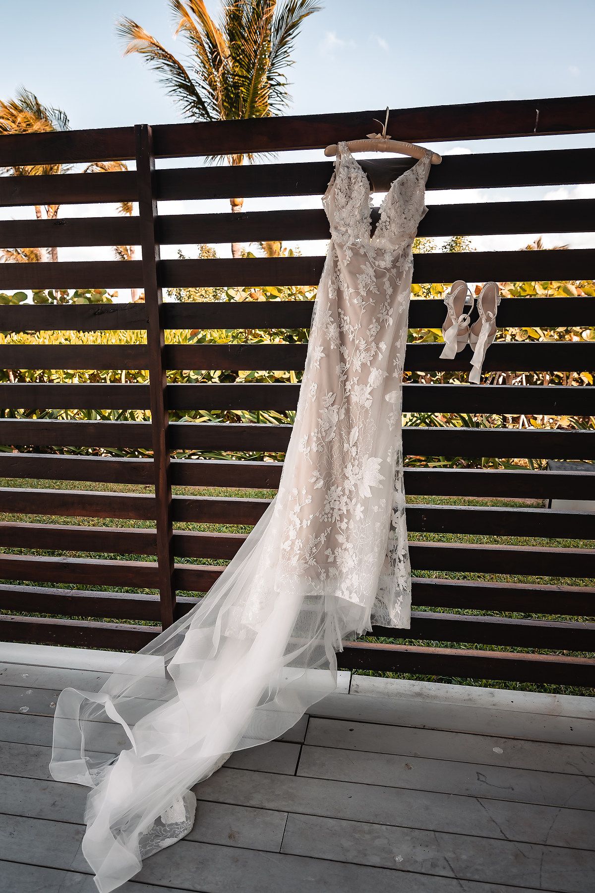 A white wedding dress veil blowing gracefully in the wind against a wooden deck railing at sunset.