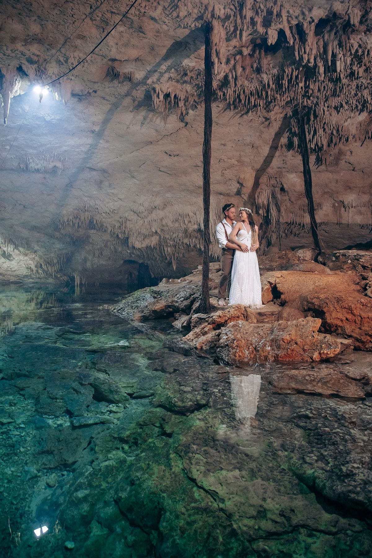 Natural cave interior showing crystal clear turquoise water and limestone formations.