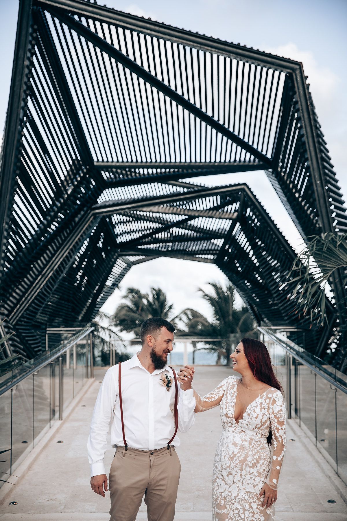 Couple shares romantic moments in a modern architectural tunnel with geometric patterns and glass walls.