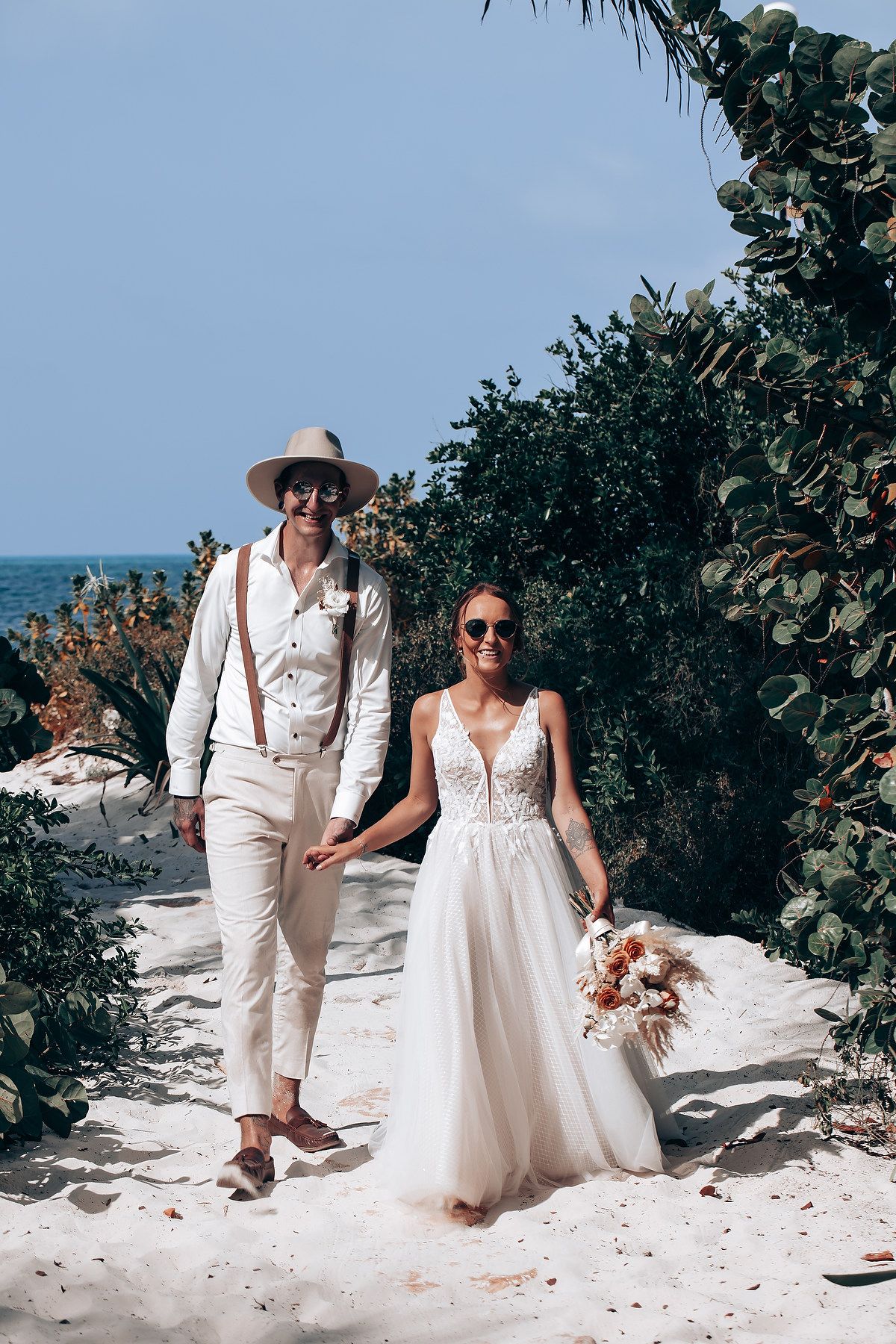 Beachside wedding photography session among tropical greenery and white sand.