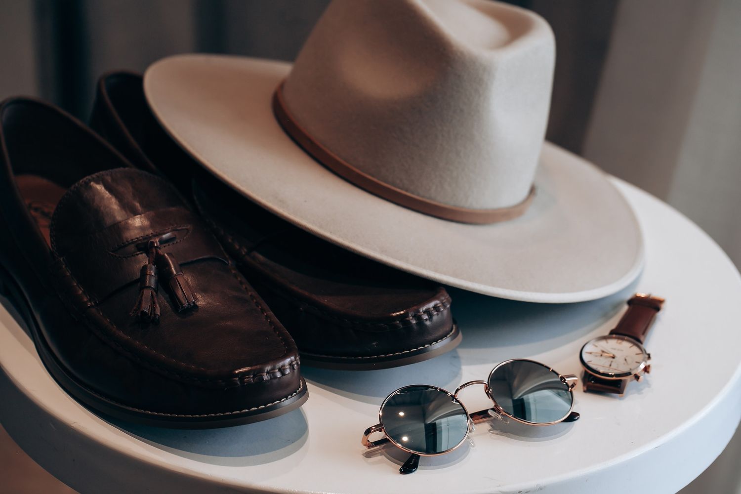 A series of photos showing brown leather loafers and a white hat arranged on a white surface.