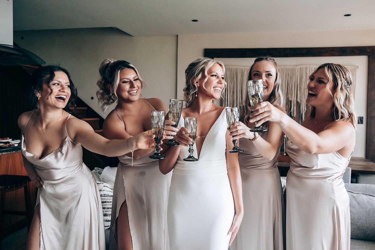 A group of women in matching white dresses pose together in a bright indoor setting.
