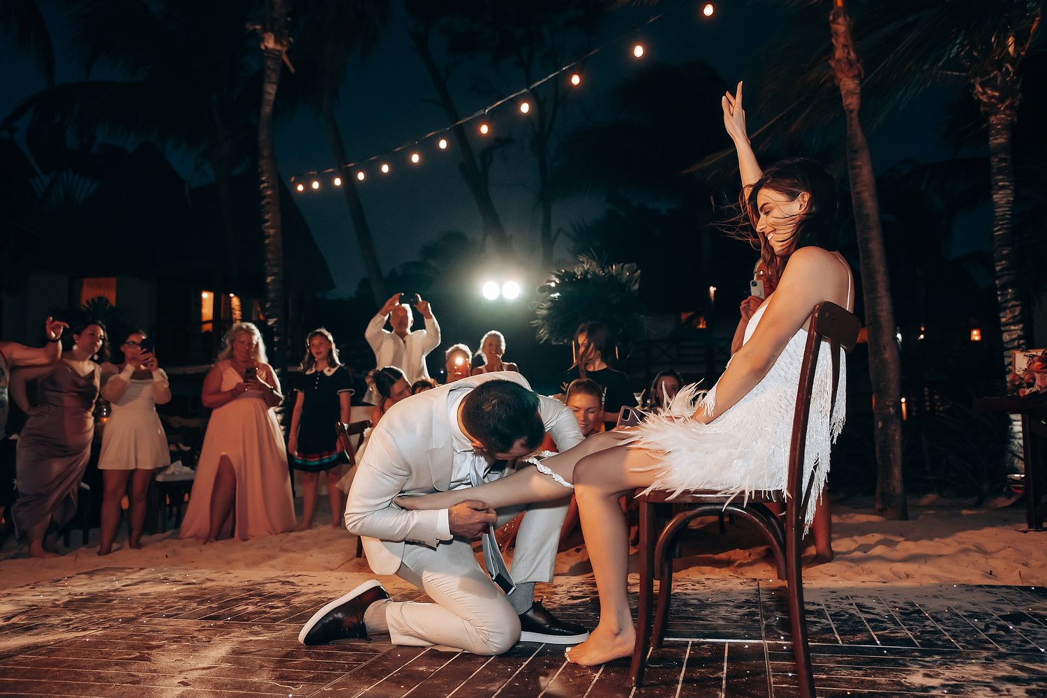 Outdoor nighttime wedding reception with string lights and dancing.