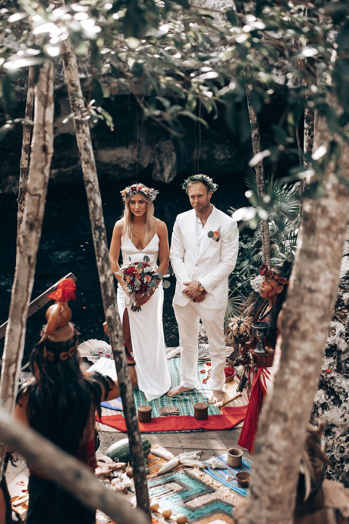 Outdoor gathering in a wooded area with blankets and decorative elements laid out for a celebration.